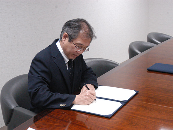 協定書に署名する島田理事長