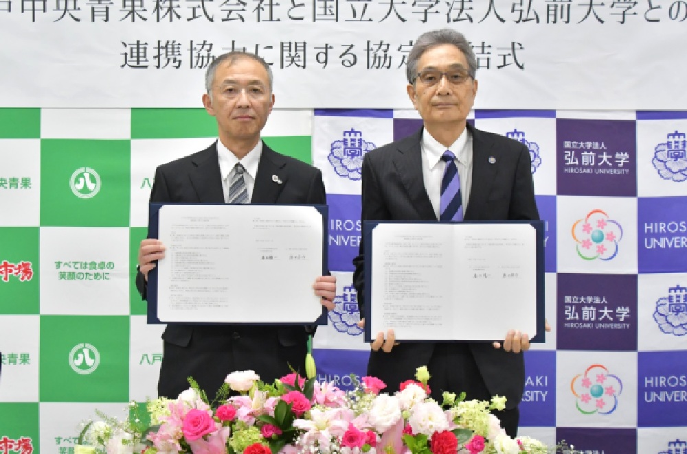 協定書を手にする宮崎支店長と福田学長